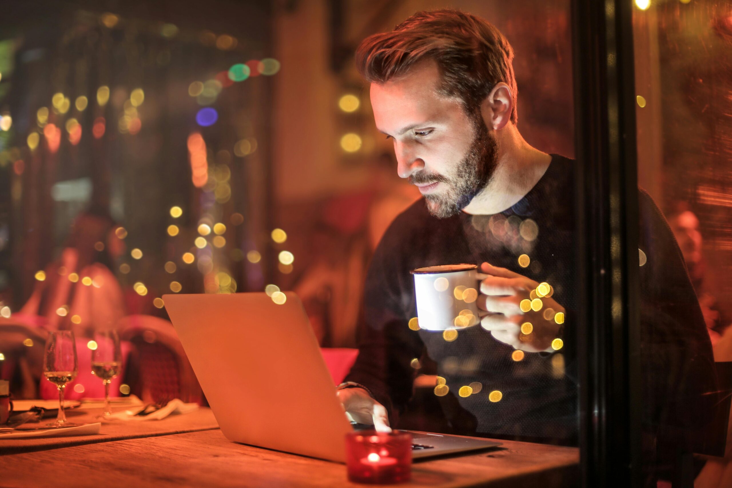 Man drinking coffee in front of laptop