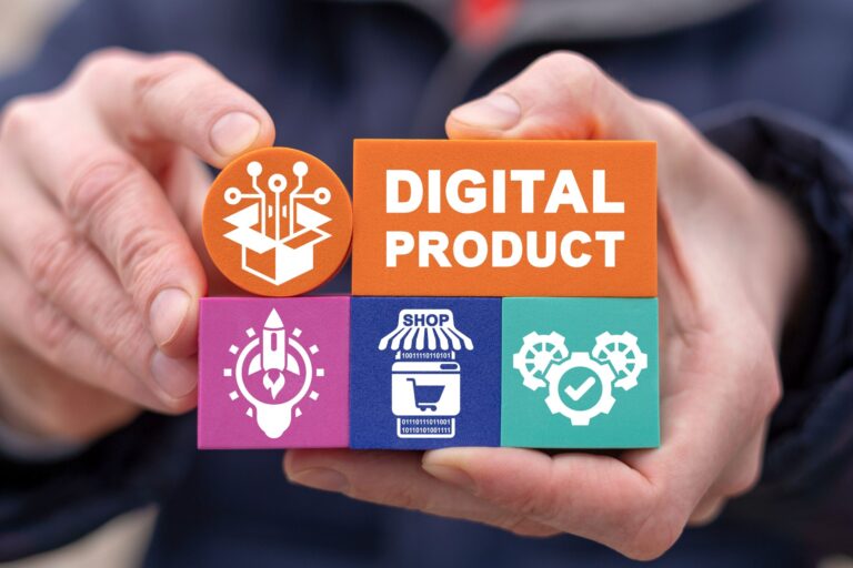 A person holds colorful foam blocks arranged in a structure representing digital products. The top orange block has "DIGITAL PRODUCT" written on it, while the surrounding blocks display various technology-related icons, including a rocket, a shopping cart, gears with a checkmark, and a digital package with circuit lines. The background is blurred, and the hands are carefully assembling the blocks, symbolizing the creation and management of digital products.