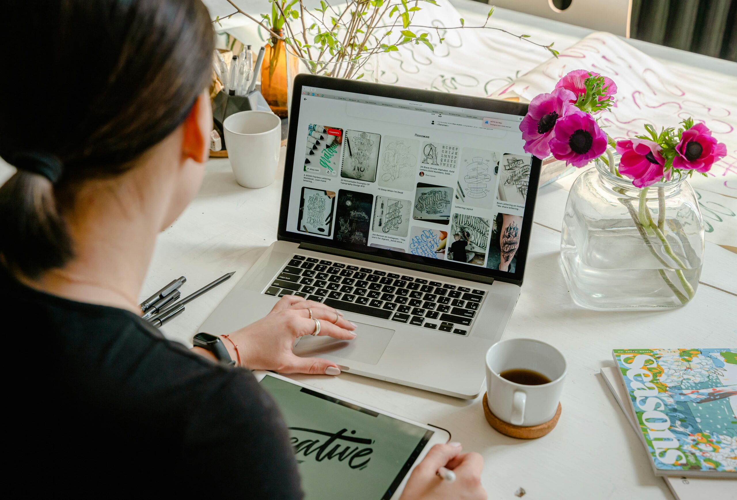 Woman building a website using a laptop and tablet at a creative workspace.